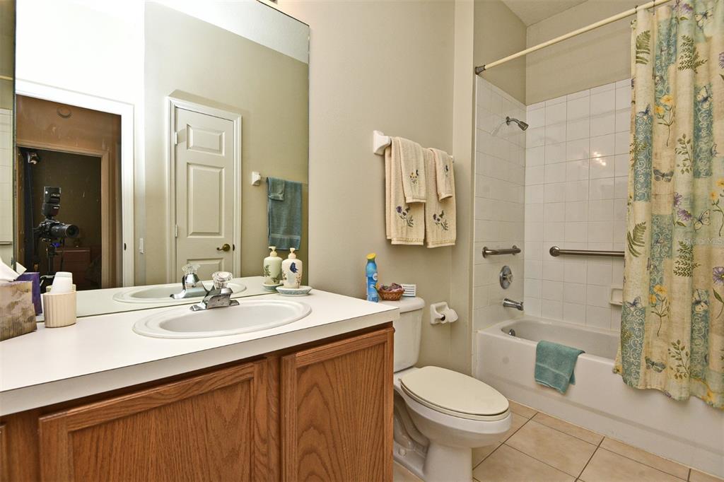 A bathroom features a wooden vanity, a white toilet, and a bathtub with a shower — 3132 RIVER BRANCH CIRCLE, KISSIMMEE, FL
