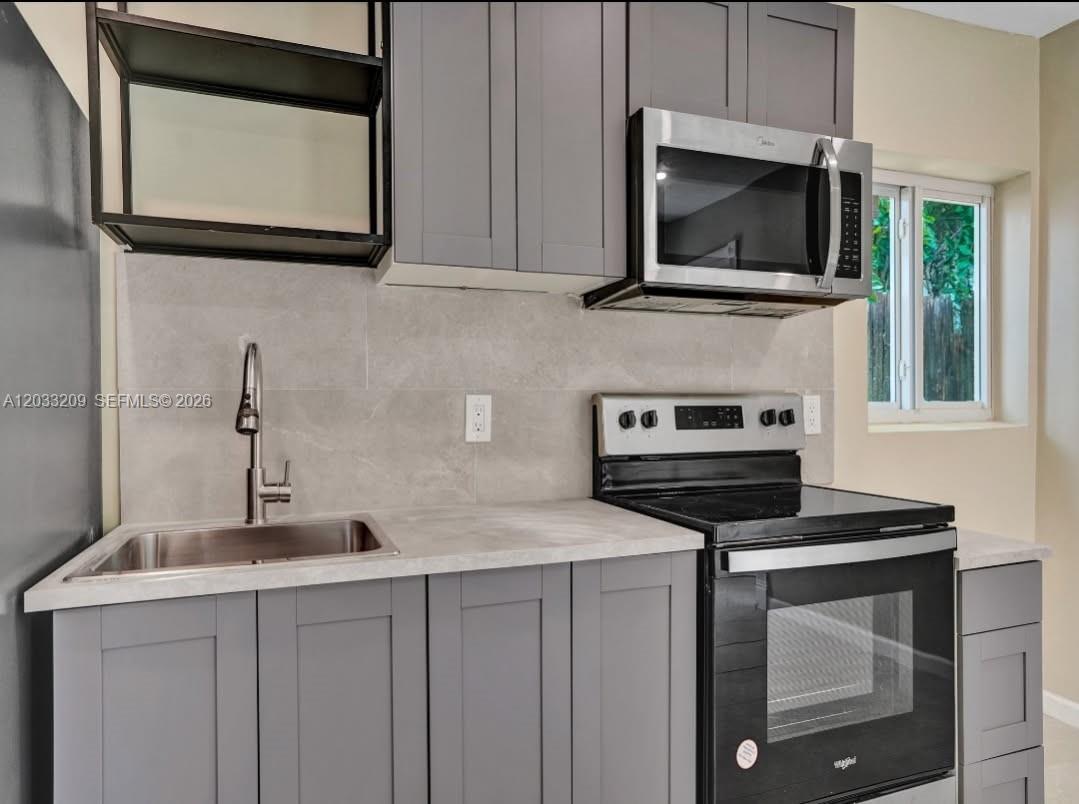 A kitchen features gray shaker cabinets, stainless steel appliances, and a light gray tiled backsplash — 2442 Garfield St # 4, Hollywood FL 33020, HOLLYWOOD, FL