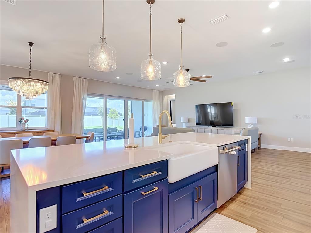 A kitchen island with blue cabinets and a farmhouse sink sits before an open living area — 8891 DRUMMER PLANK DRIVE, WESLEY CHAPEL, FL