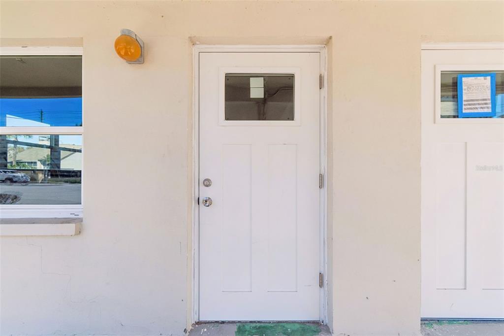 A white exterior wall features a single door with a window and a nearby window — 4565 DUHME ROAD UNIT 101, ST PETERSBURG, FL