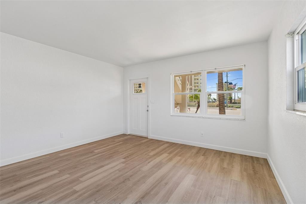 An empty room with white walls, wood-look flooring, a white door, and a large window — 4565 DUHME ROAD UNIT 101, ST PETERSBURG, FL