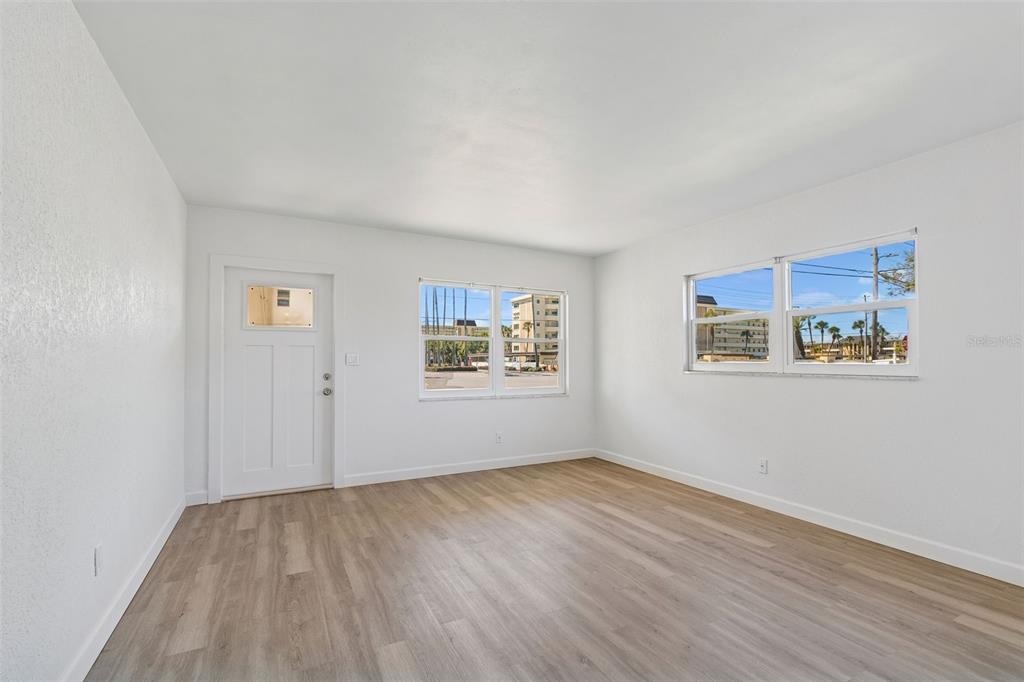 A bright, empty room features white walls, light wood-look flooring, and two windows — 4565 DUHME ROAD UNIT 101, ST PETERSBURG, FL