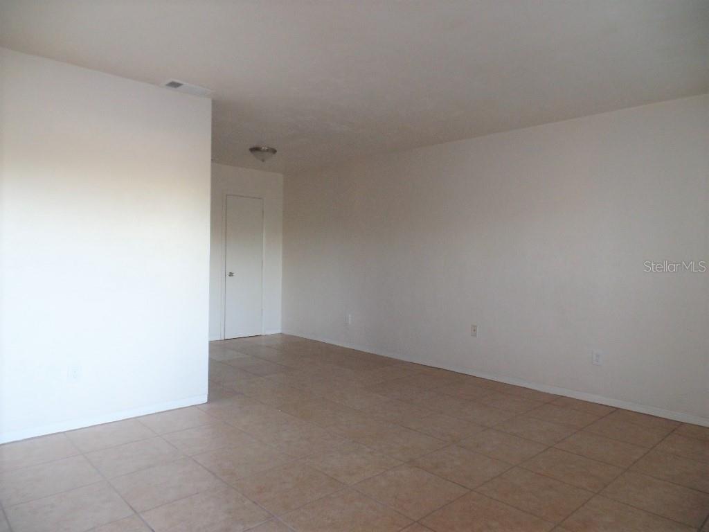An empty room features white walls, a tiled floor, and a closed white door — 1240 70TH STREET N UNIT 7, ST PETERSBURG, FL