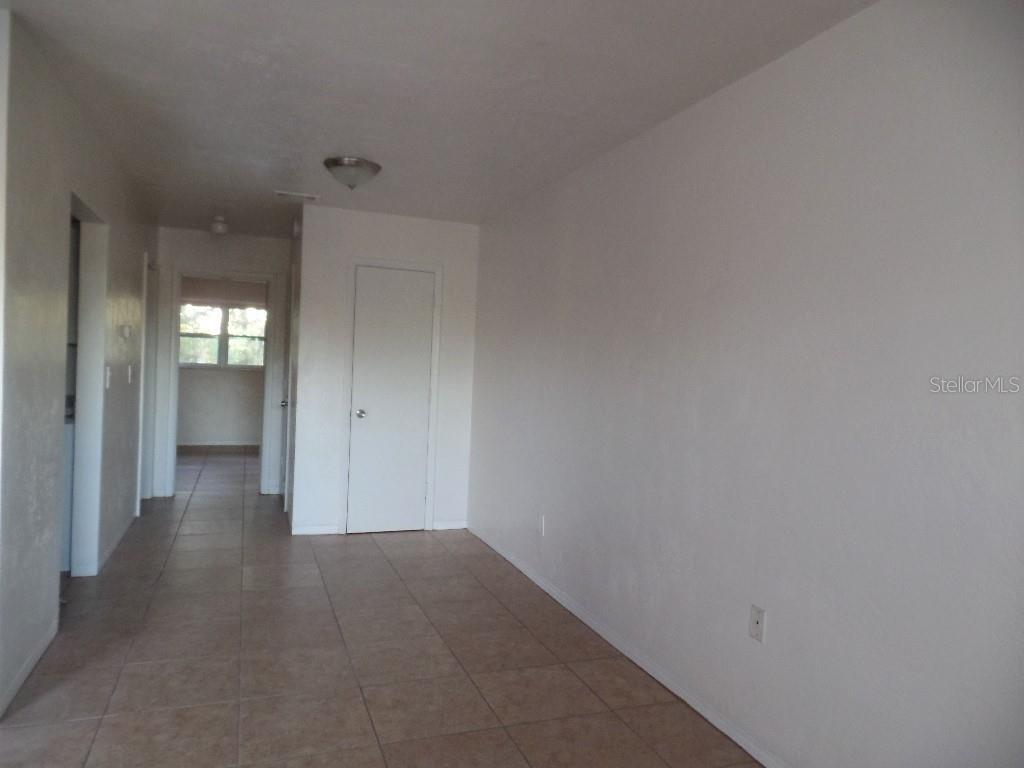 A room with light-colored tile flooring, white walls, and a closed interior door — 1240 70TH STREET N UNIT 7, ST PETERSBURG, FL