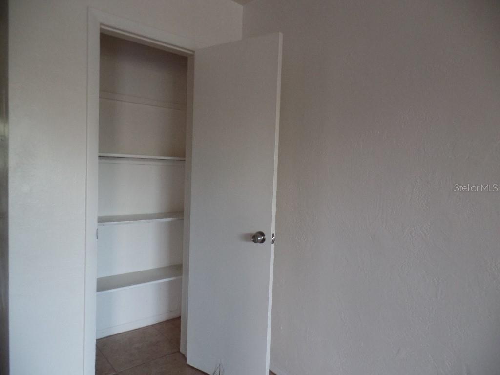 An open white door reveals a closet with multiple interior shelves — 1240 70TH STREET N UNIT 7, ST PETERSBURG, FL