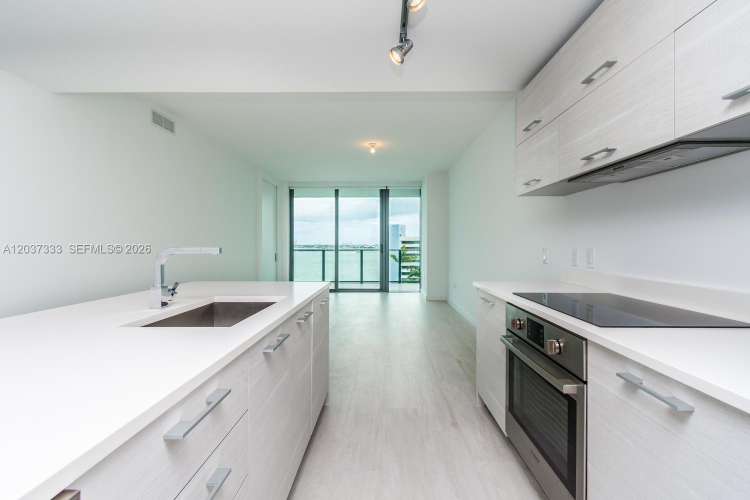 A modern kitchen features light wood cabinetry, white countertops, and a view of the water — 650 NE 32nd St # 805, Miami FL 33137, MIAMI, FL