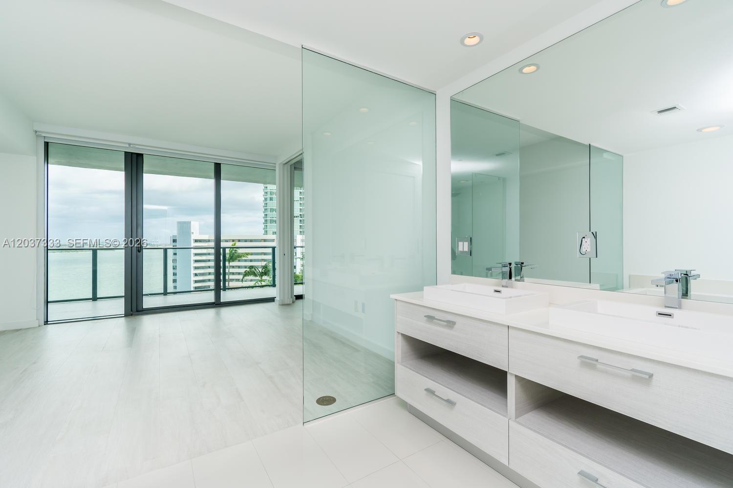 A modern bathroom features a double vanity with white countertops and a glass-enclosed shower area — 650 NE 32nd St # 805, Miami FL 33137, MIAMI, FL