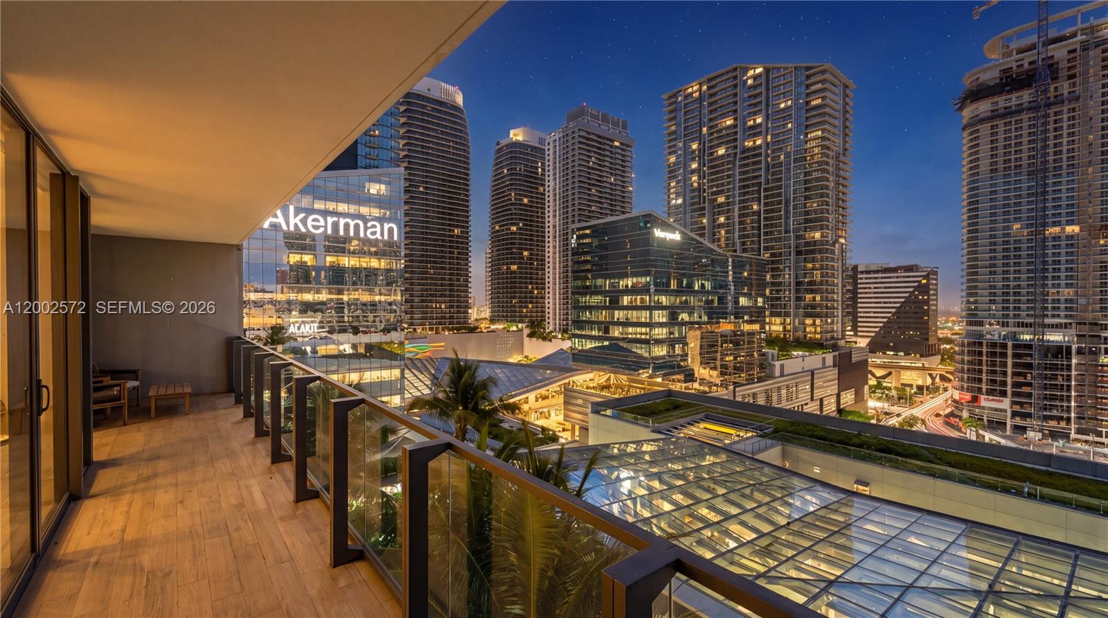 A balcony with wood-look flooring overlooks a city skyline at night — 68 SE 6th St # 1106, Miami FL 33131, MIAMI, FL