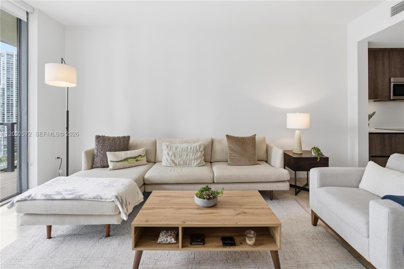 A living room features a sectional sofa, a wooden coffee table, and a floor lamp — 68 SE 6th St # 1106, Miami FL 33131, MIAMI, FL