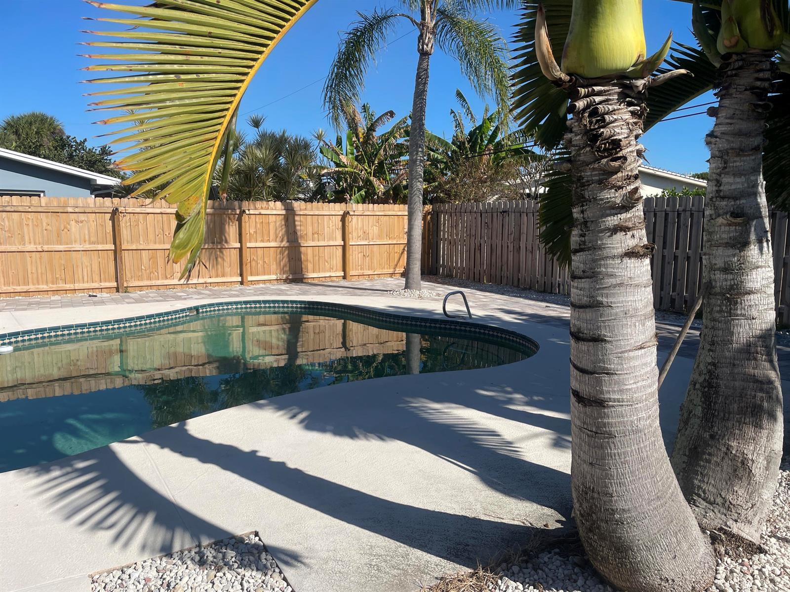 A swimming pool with a concrete deck and palm trees in a fenced backyard — 104 Jupiter Court, Indialantic FL 32903, INDIALANTIC, FL