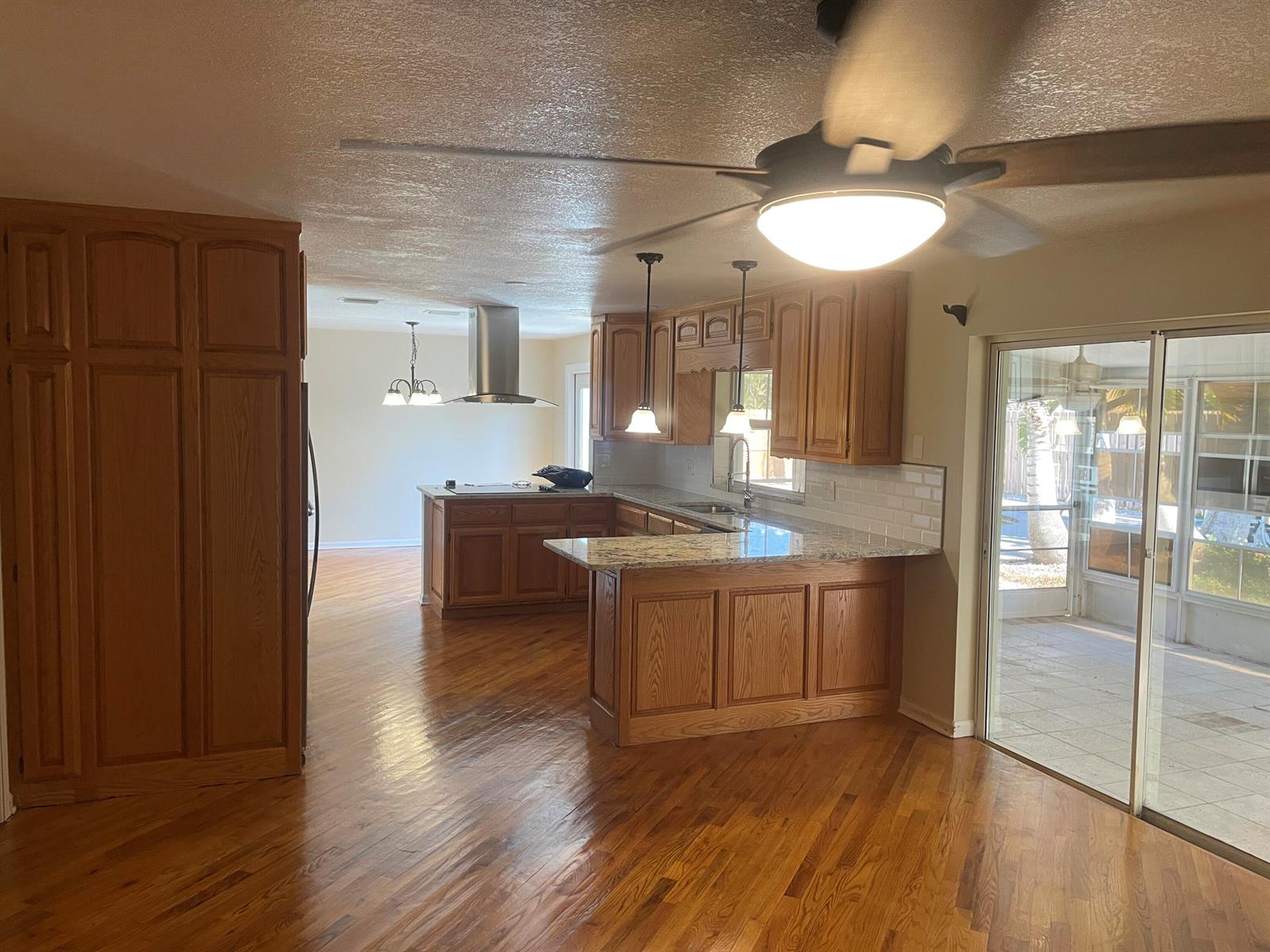 A kitchen with oak cabinets, granite countertops, and hardwood floors opens to a dining area — 104 Jupiter Court, Indialantic FL 32903, INDIALANTIC, FL