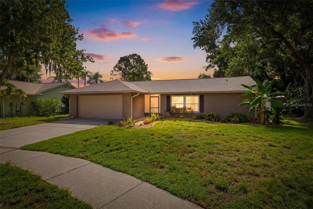 A single-story house with a tan exterior, a two-car garage, and a front lawn — 14801 PERRIWINKLE PLACE, TAMPA, FL