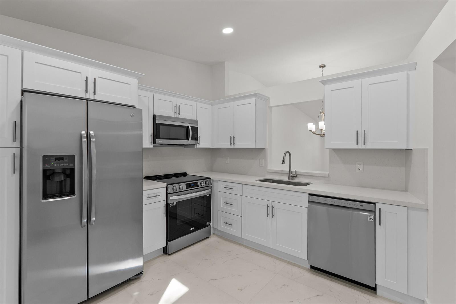 A kitchen features white cabinets, stainless steel appliances, and light-colored countertops — 8273 Springtree Road, Boca Raton FL 33496, BOCA RATON, FL