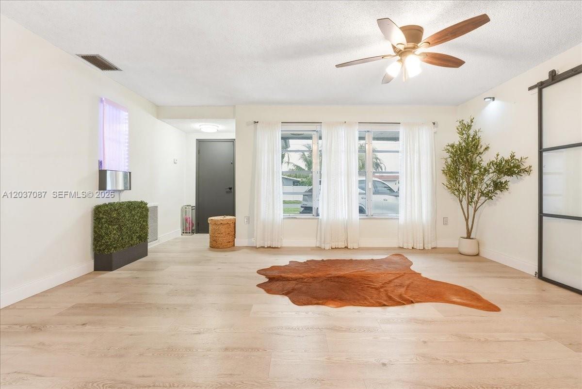 A living room features light wood-look flooring, a ceiling fan, and a cowhide rug — 8580 NW 20th Ct, Sunrise FL 33322, SUNRISE, FL
