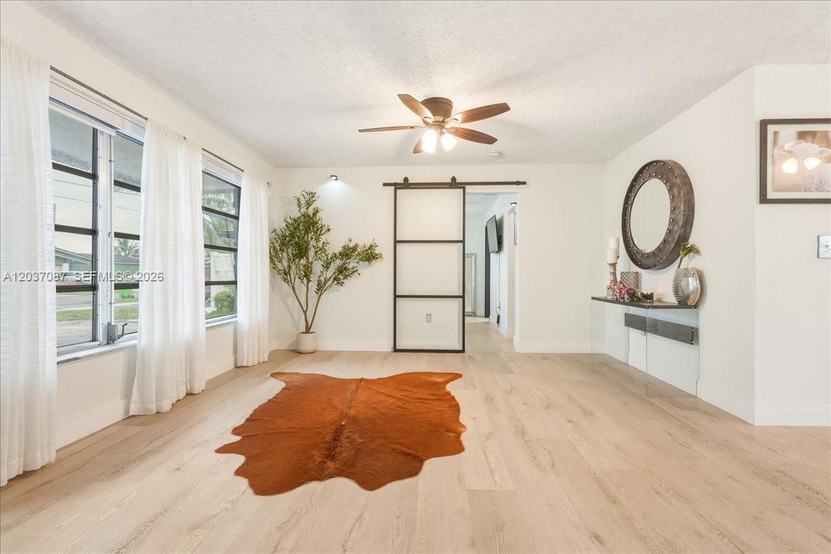 A bright room features light wood flooring, a sliding barn door, and a cowhide rug — 8580 NW 20th Ct, Sunrise FL 33322, SUNRISE, FL