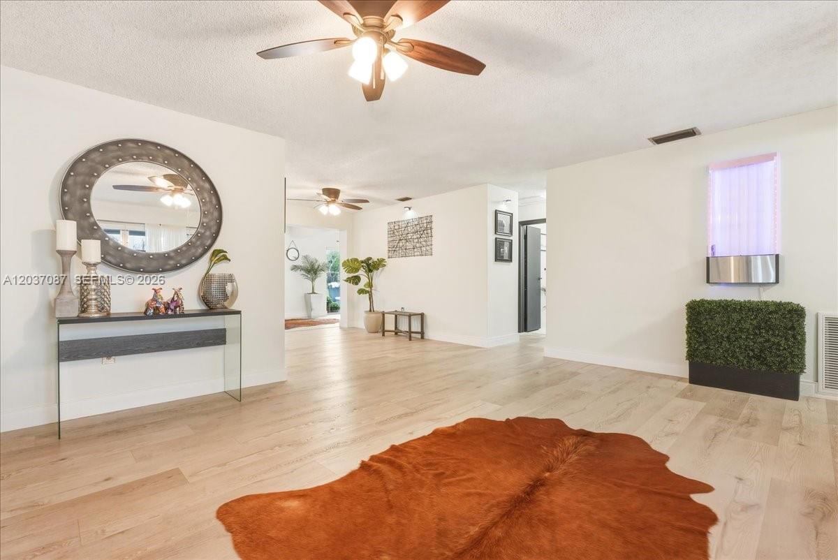 A living room features light wood flooring, a brown cowhide rug, and a circular mirror — 8580 NW 20th Ct, Sunrise FL 33322, SUNRISE, FL