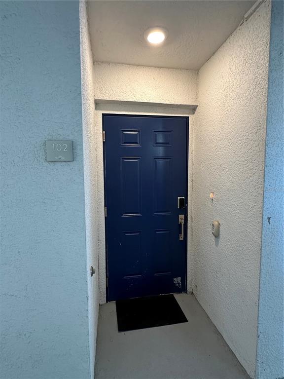 A blue front door with a number 102 sign sits in a recessed entryway — 3180 PARADOX CIRCLE UNIT 102, KISSIMMEE, FL
