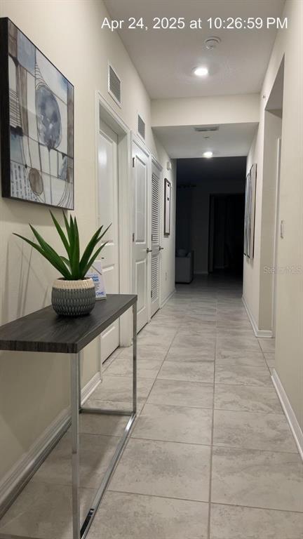 A hallway with light tile flooring, a console table with a plant, and closed doors — 3180 PARADOX CIRCLE UNIT 102, KISSIMMEE, FL
