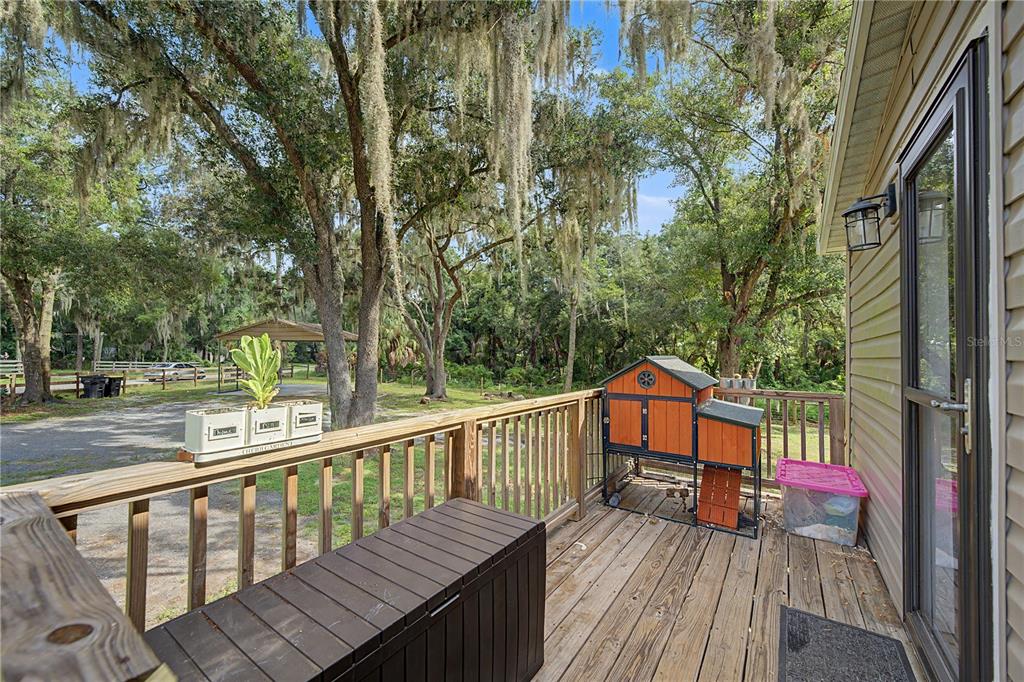 A wooden deck features a storage bench, a chicken coop, and a small planter — 3935 EWELL ROAD, LAKELAND, FL
