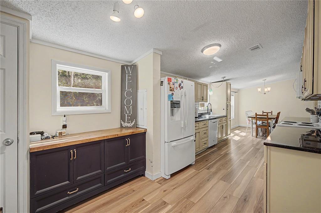 A kitchen with dark blue cabinets, a white refrigerator, and light wood-look flooring — 3935 EWELL ROAD, LAKELAND, FL