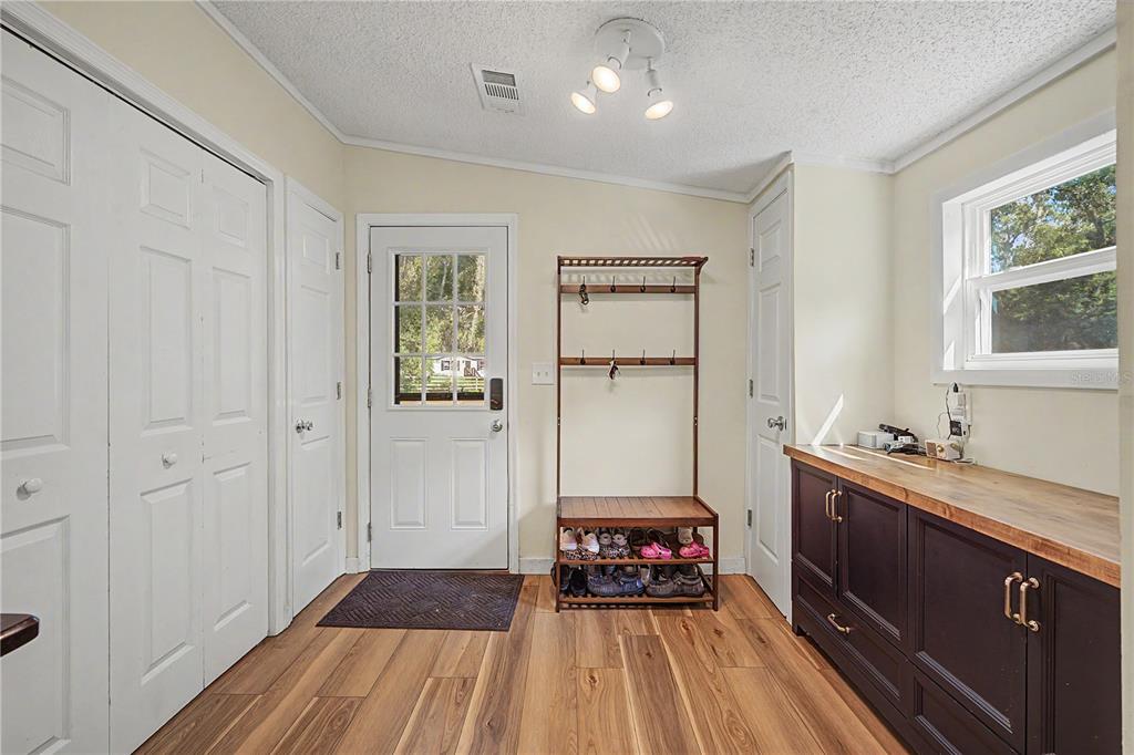A mudroom features wood-look flooring, a coat rack with shoe storage, and dark cabinetry — 3935 EWELL ROAD, LAKELAND, FL