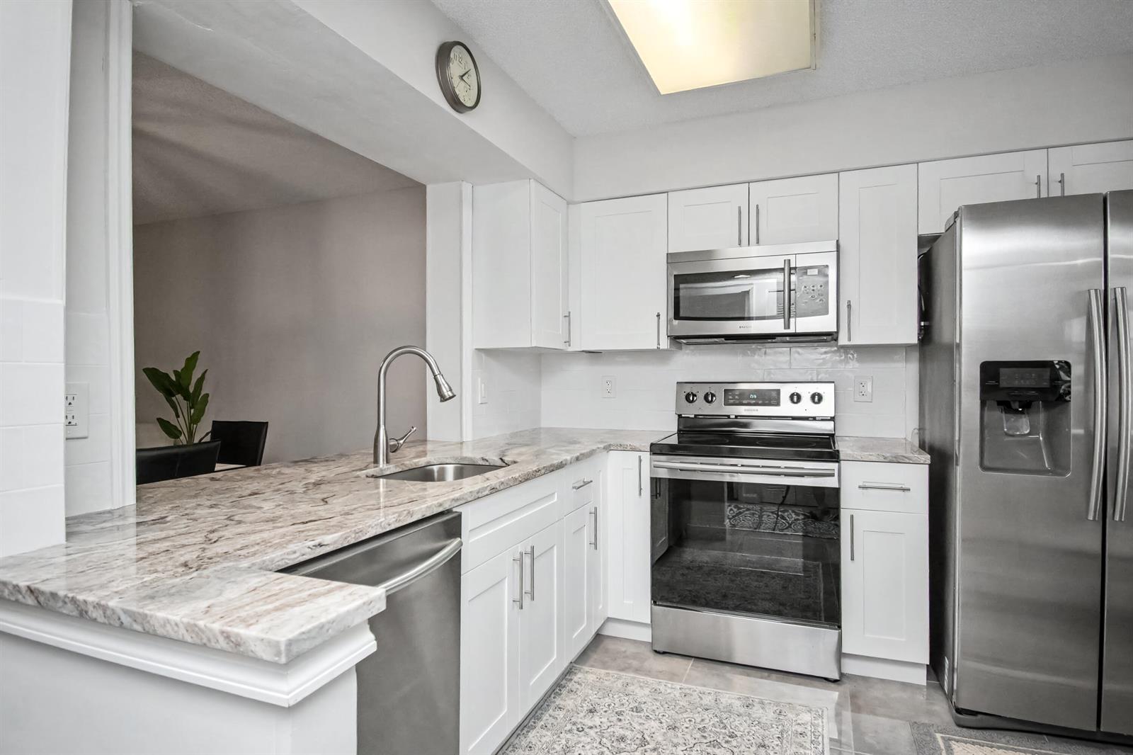 A kitchen featuring white cabinets, stainless steel appliances, and granite countertops — 7351 Kinghurst Drive # 301, Delray Beach FL 33446, DELRAY BEACH, FL