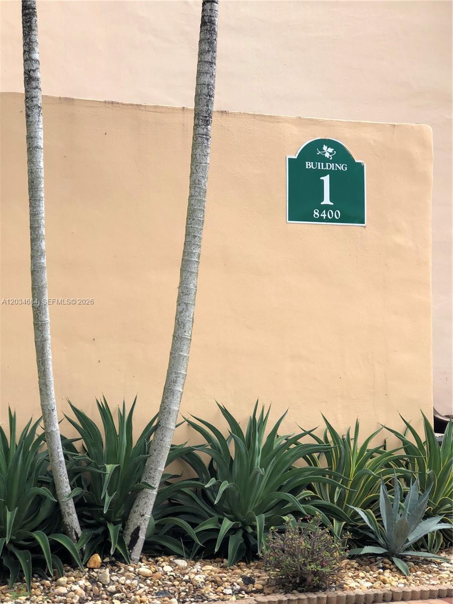 A green sign labeled Building 1 and 8400 is mounted on a beige exterior wall — 8400 SW 133rd Ave Rd # 324, Miami FL 33183, MIAMI, FL