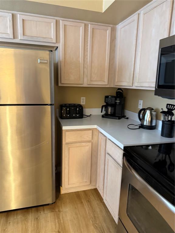 A kitchen features light wood cabinets, stainless steel appliances, and a white countertop — 1122 CLEAR CREEK CIRCLE, CLERMONT, FL