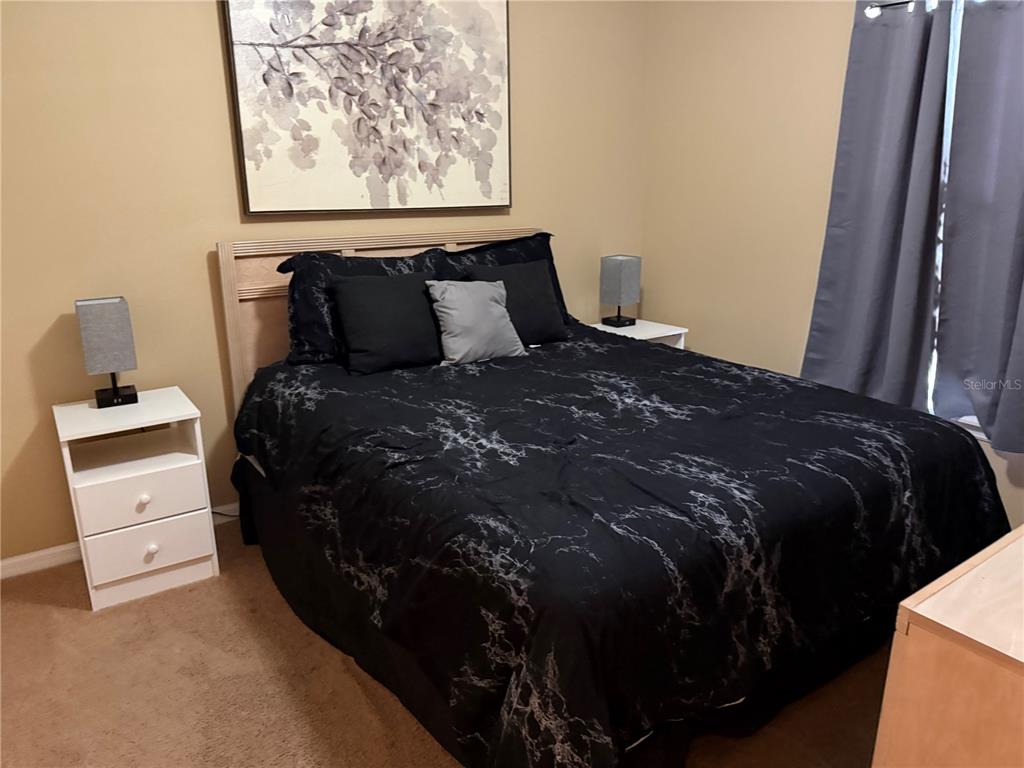 A bedroom features a bed with black marble-patterned bedding, two nightstands, and wall art — 1122 CLEAR CREEK CIRCLE, CLERMONT, FL
