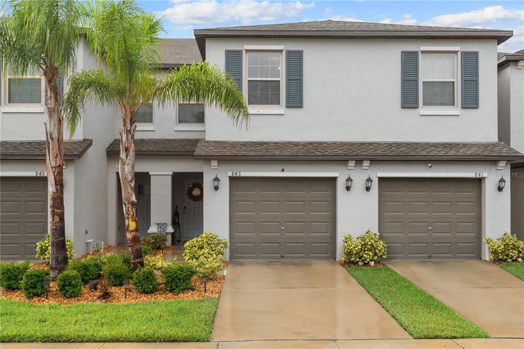 A row of three two-story townhomes with gray stucco exteriors and attached garages — 843 ROYAL EMPRESS DRIVE, RUSKIN, FL