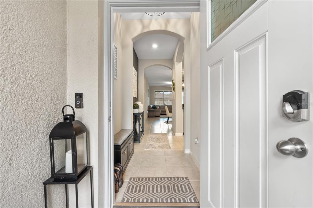 A view through an open front door into a tiled entryway with an arched hallway — 843 ROYAL EMPRESS DRIVE, RUSKIN, FL