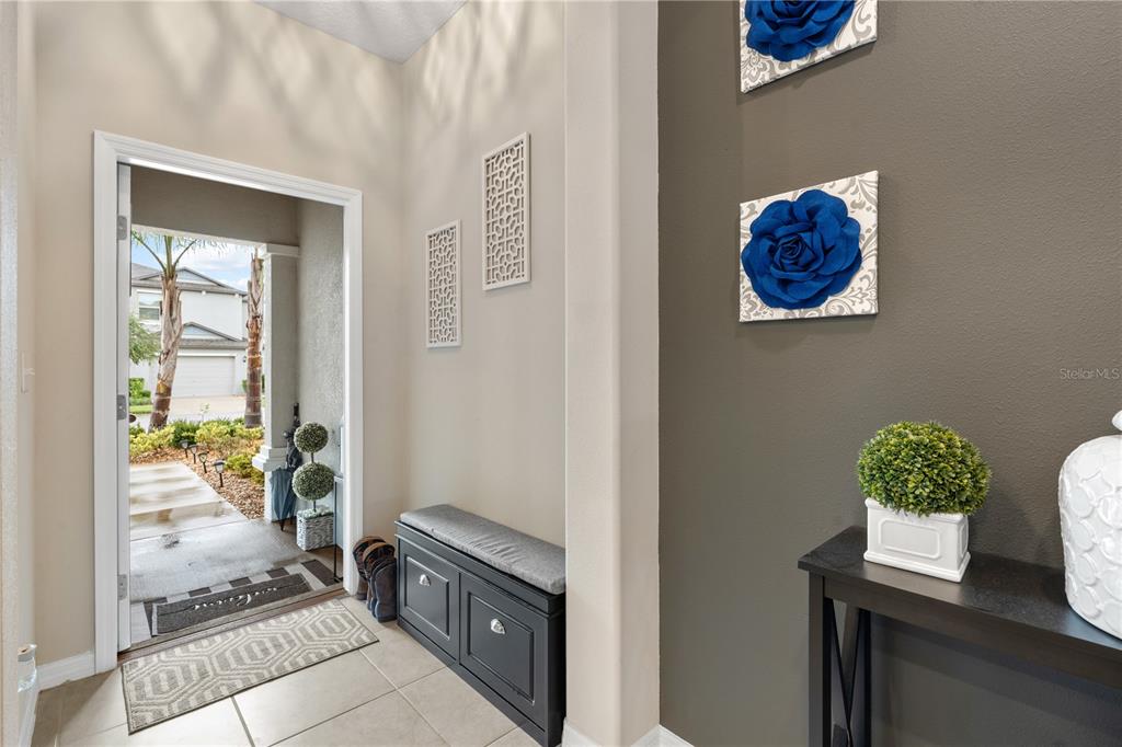 An entryway features a dark gray accent wall with floral art, a bench, and tile flooring — 843 ROYAL EMPRESS DRIVE, RUSKIN, FL