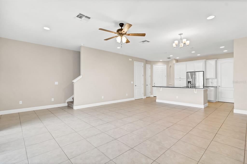 An open-concept living area with tile flooring, a ceiling fan, and an adjacent kitchen — 14481 SWANLEY STREET, ORLANDO, FL