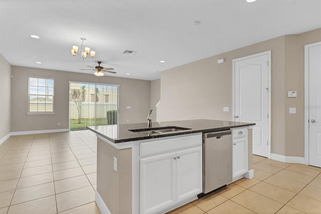A kitchen island with a dark countertop and stainless dishwasher faces a bright living area — 14481 SWANLEY STREET, ORLANDO, FL