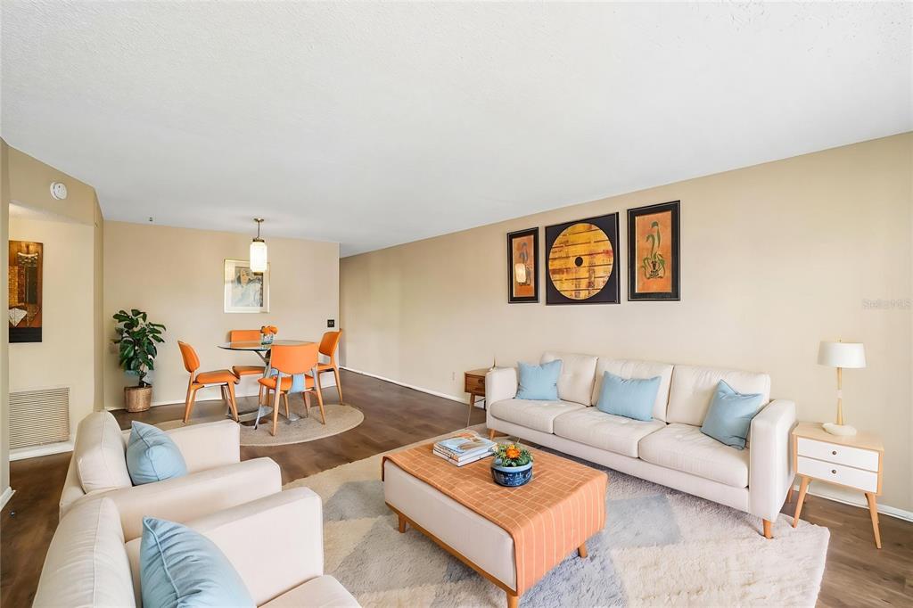 A living and dining room with beige walls, light-colored furniture, and wood-look flooring — 2402 ECUADORIAN WAY UNIT 28, CLEARWATER, FL