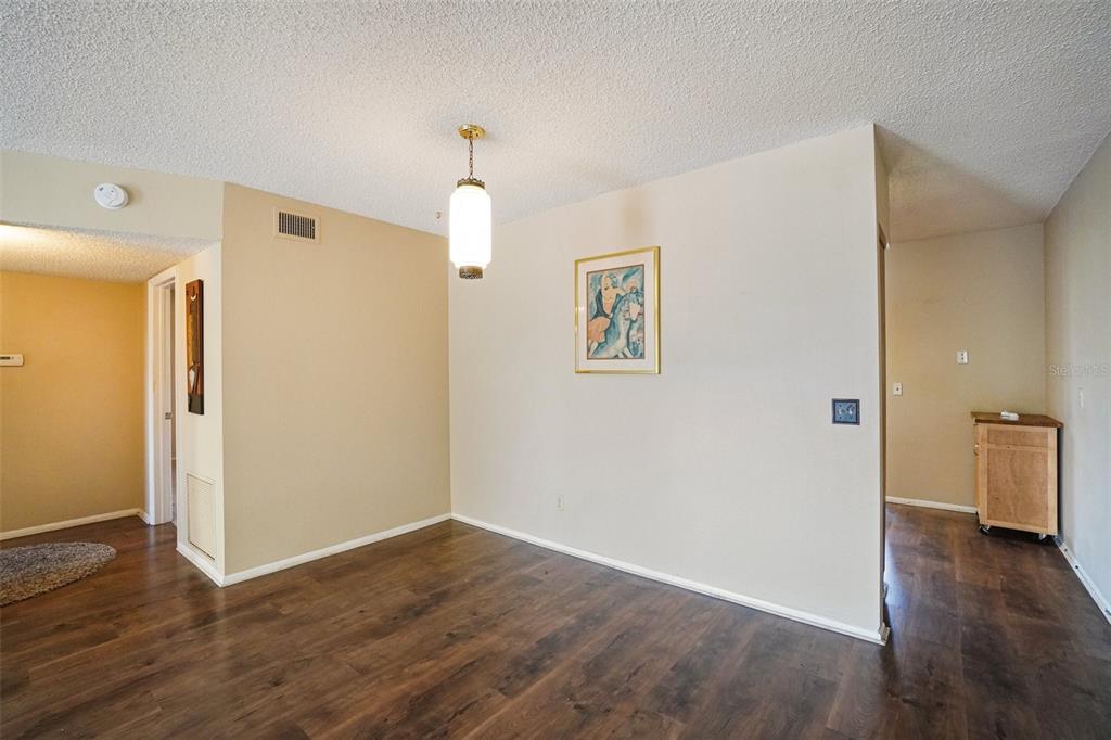 An empty dining area features wood-look flooring, a pendant light, and a framed wall print — 2402 ECUADORIAN WAY UNIT 28, CLEARWATER, FL
