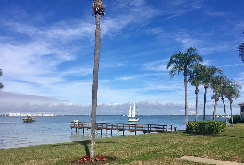 A wooden pier extends into a bay with a sailboat and a boat nearby — 6211 SUN BOULEVARD UNIT 306, ST PETERSBURG, FL