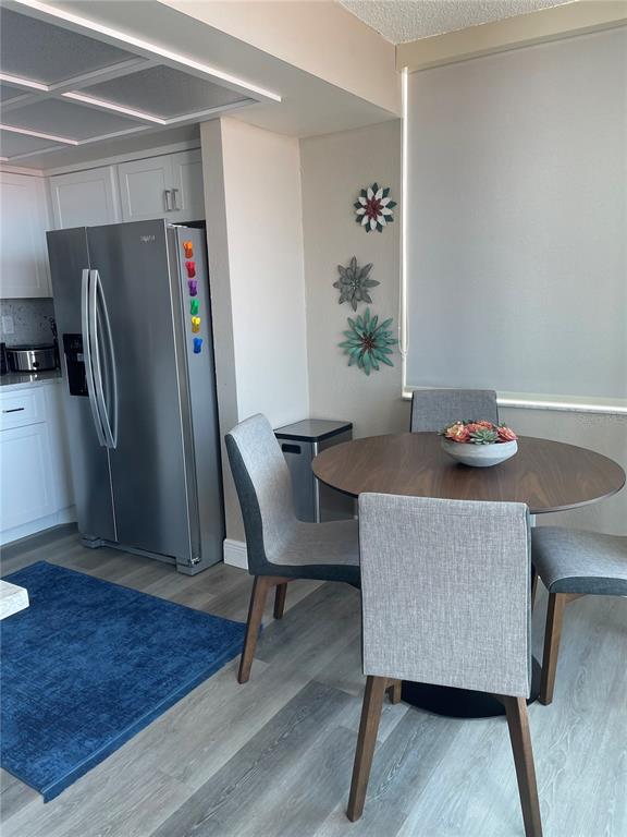 A dining area features a round wooden table, four gray chairs, and a stainless steel refrigerator — 6211 SUN BOULEVARD UNIT 306, ST PETERSBURG, FL