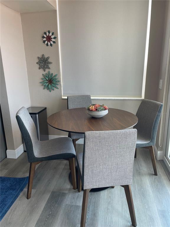 A dining area features a round wooden table with four gray upholstered chairs and wall decor — 6211 SUN BOULEVARD UNIT 306, ST PETERSBURG, FL