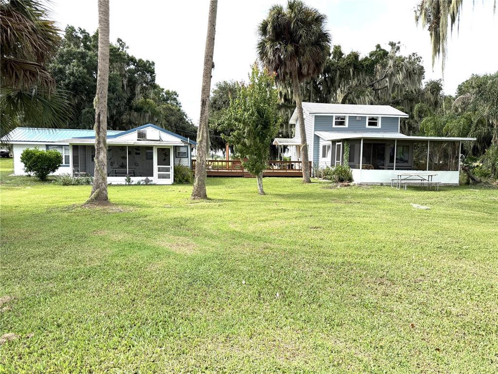 Two detached houses with screened porches sit on a grassy lot with tall palm trees — 1973 N LAKE REEDY BOULEVARD, FROSTPROOF, FL