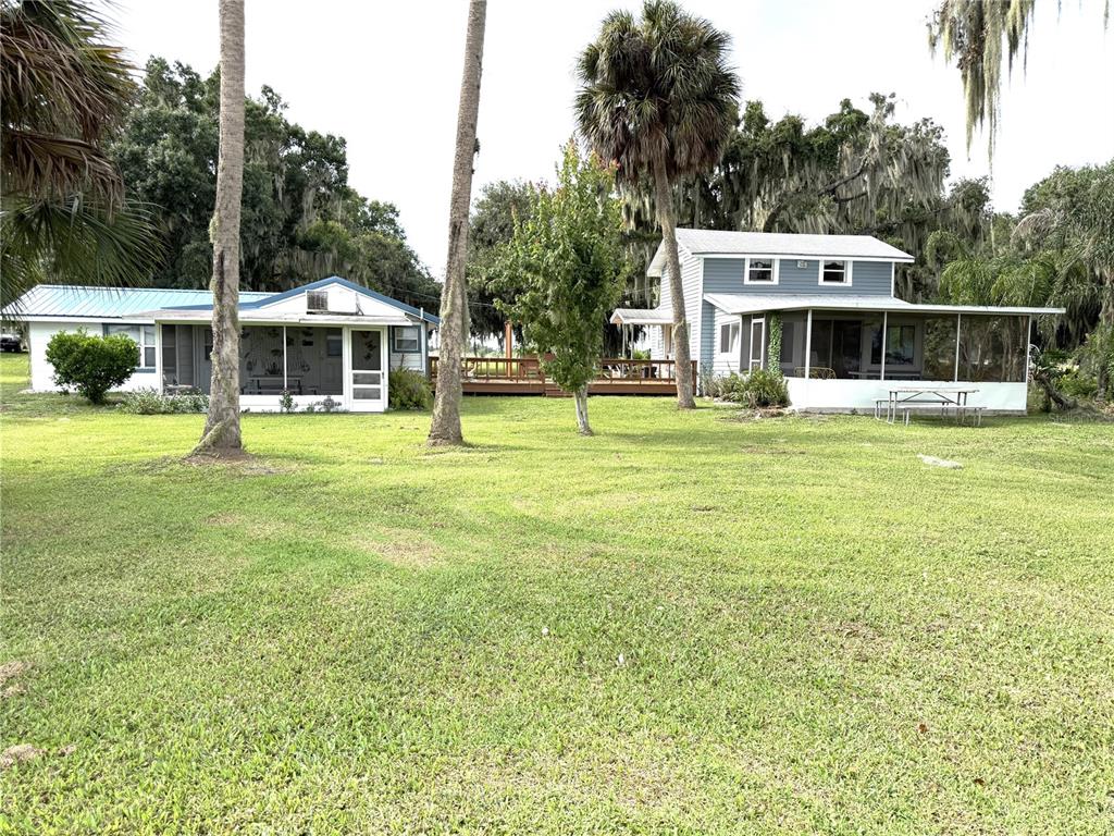 Two houses with screened porches sit on a large grassy lawn with palm trees — 1973 N LAKE REEDY BOULEVARD, FROSTPROOF, FL