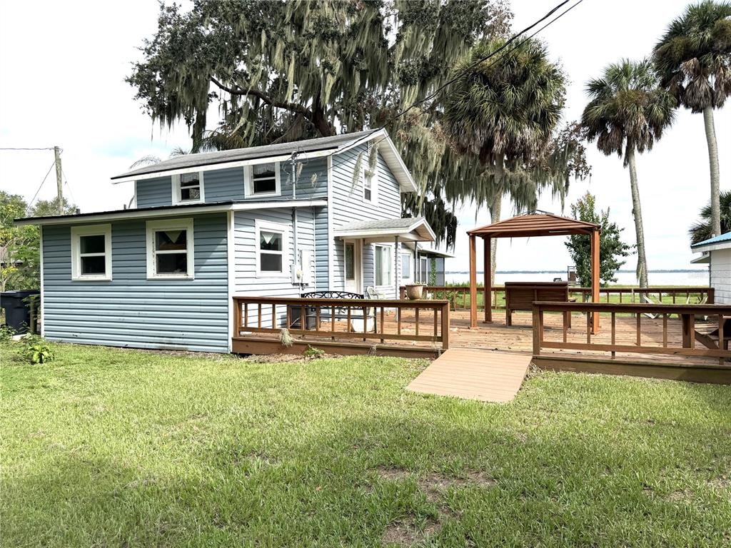 A blue two-story house with a wooden deck and gazebo overlooking a lake — 1973 N LAKE REEDY BOULEVARD, FROSTPROOF, FL