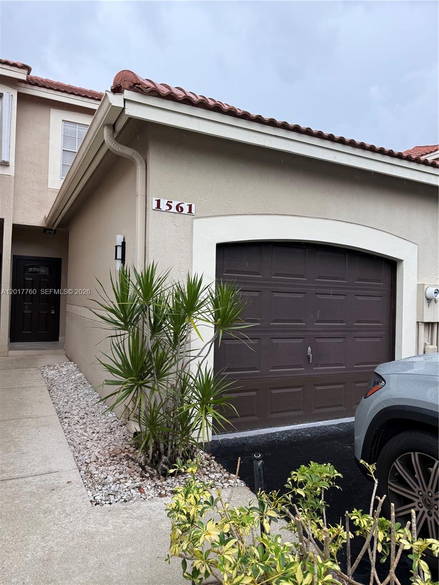 A tan stucco townhouse exterior features a brown garage door and a dark front door — WESTON, FL