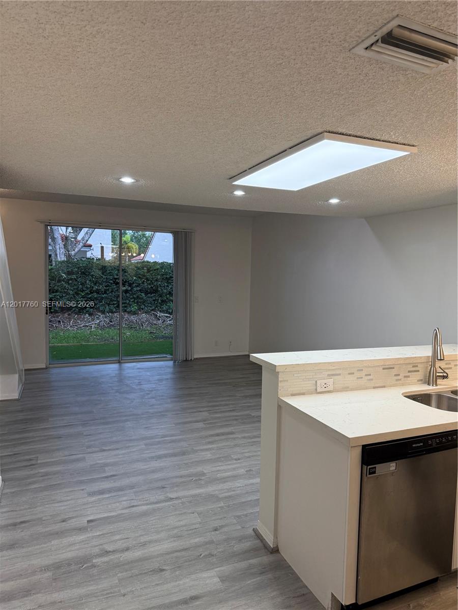 A kitchen with a stainless steel dishwasher overlooks a living area with sliding glass doors — WESTON, FL