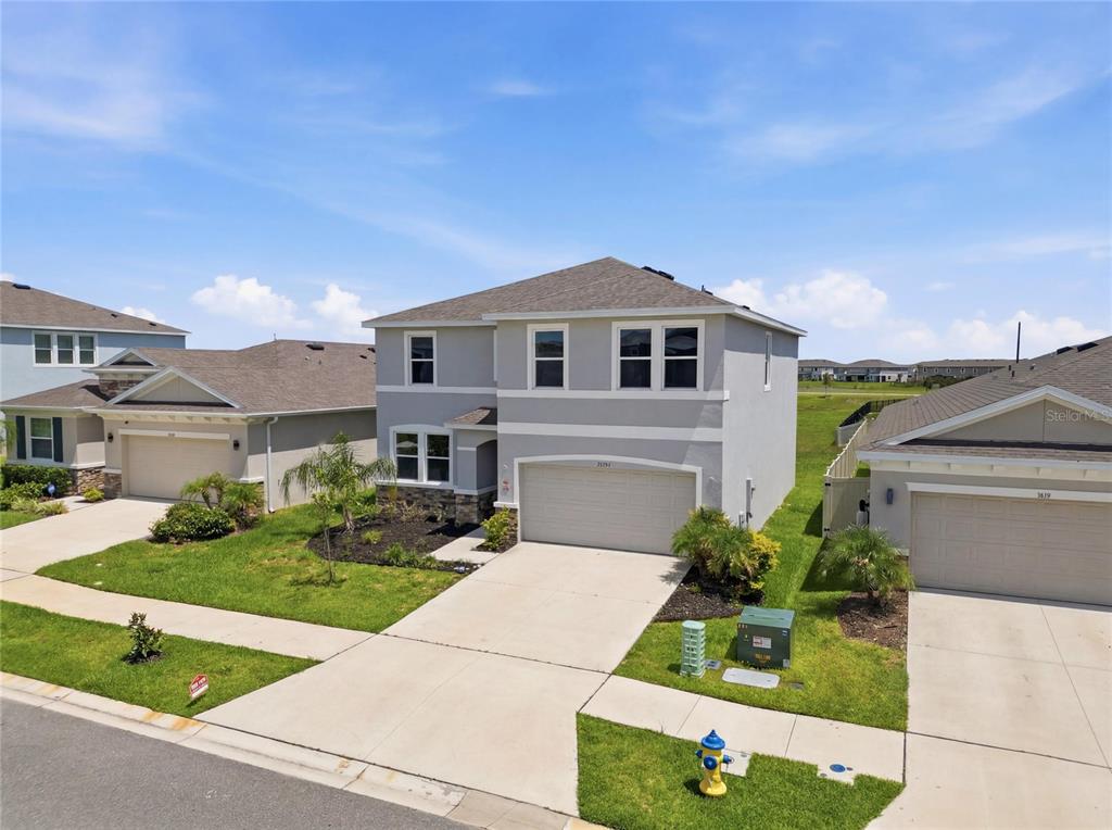 An exterior view of a two-story suburban house with a gray facade and attached garage — 32107 CONCHSHELL SAIL STREET, WESLEY CHAPEL, FL