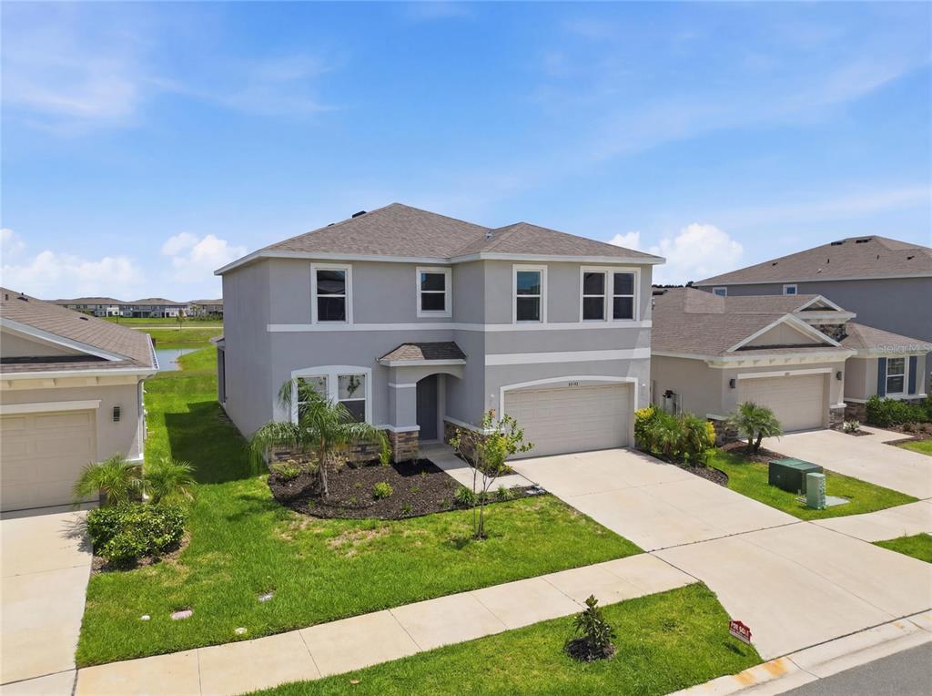 A two-story suburban house with a gray exterior, a two-car garage, and a lawn — 32107 CONCHSHELL SAIL STREET, WESLEY CHAPEL, FL