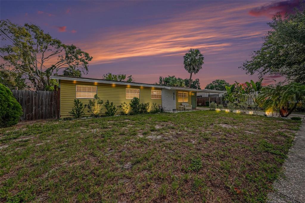 A single-story house with yellow siding and a front lawn under a sunset sky — 4733 W WISCONSIN AVENUE, TAMPA, FL