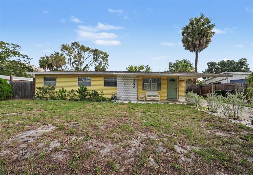 A yellow single-story house with a white brick accent wall and a covered carport — 4733 W WISCONSIN AVENUE, TAMPA, FL