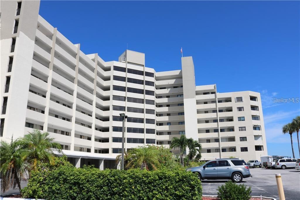 A multi-story, white concrete apartment building stands under a clear blue sky — 6035 SEA RANCH DRIVE UNIT 410, HUDSON, FL