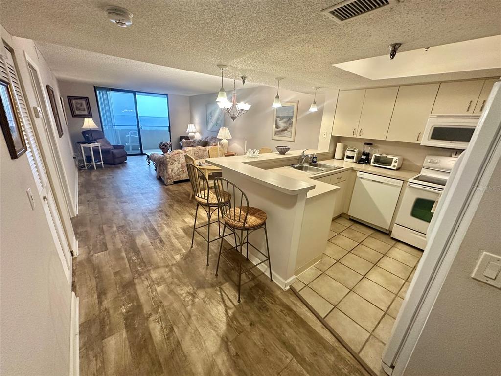 An open-concept kitchen with a breakfast bar overlooks a living area with ocean views — 6035 SEA RANCH DRIVE UNIT 410, HUDSON, FL